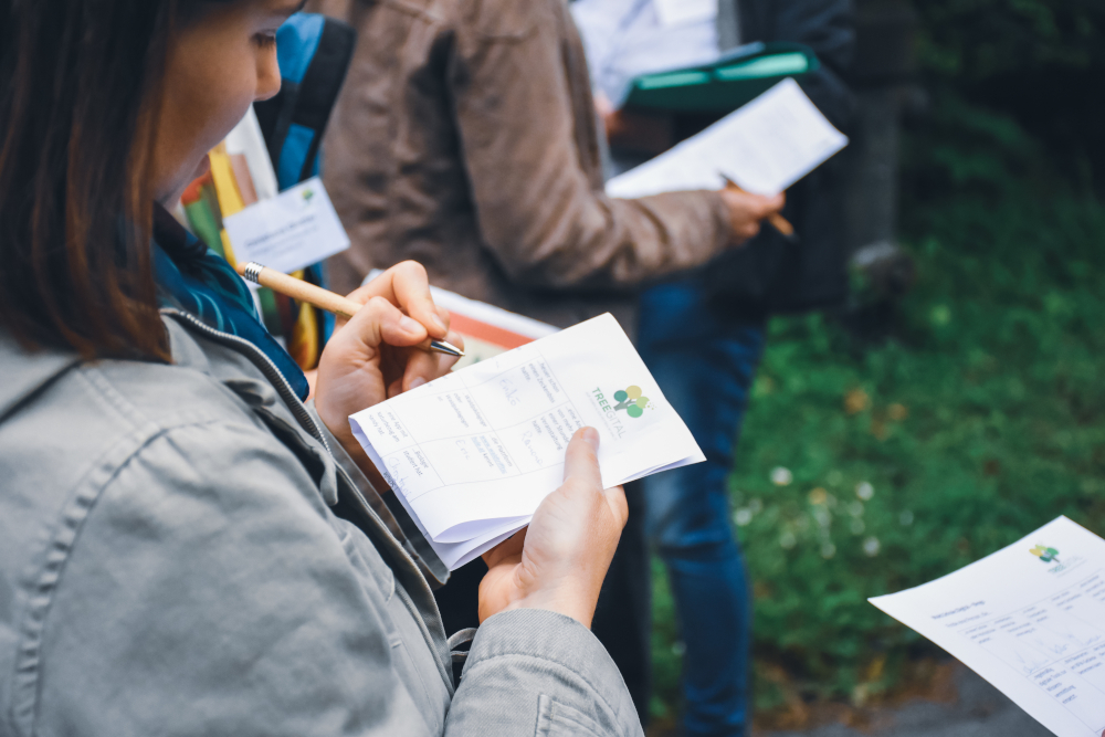 Teilnehmer:innen im Freien unterwegs mit einem Notizblock und Stift